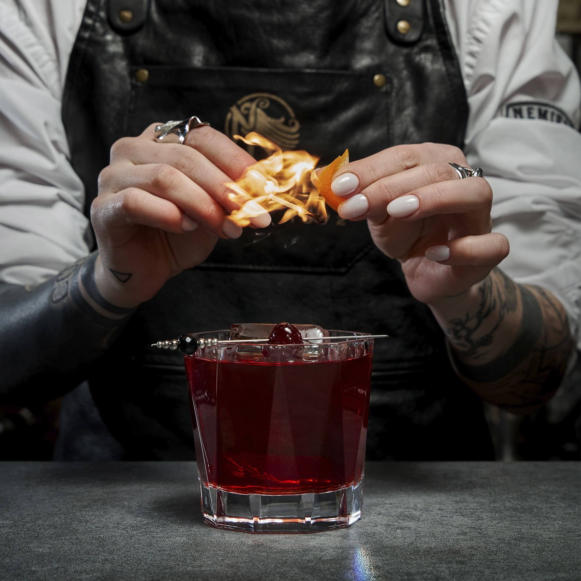 Bartender flaming orange peel over a Nemiroff Negroski cocktail